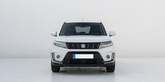 Front view of a white Suzuki Vitara compact SUV parked against a clean, plain white studio wall.
